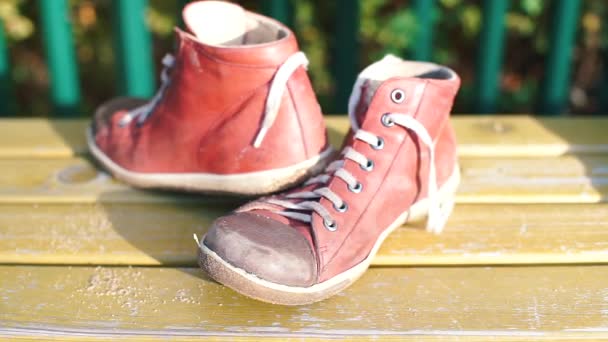 Красные туфли стоят на желтой скамейке под солнцем — стоковое видео