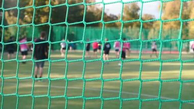 Bir spor ağının yakın çekimi. Arka planda futbol oynuyorlar..