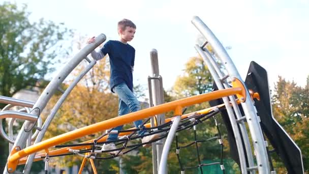 Menino chuta na grade do playground — Vídeo de Stock