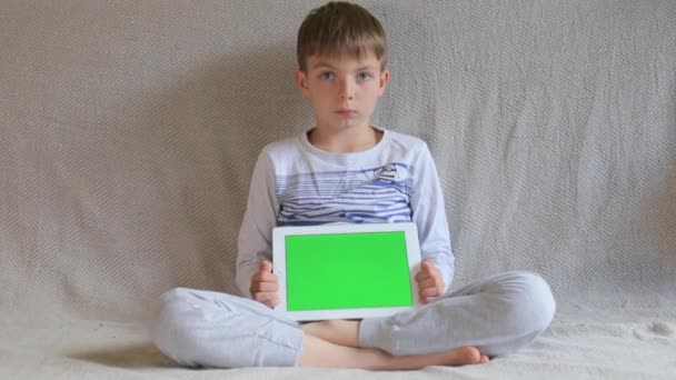 Chico con una cara seria muestra una tableta — Vídeo de stock