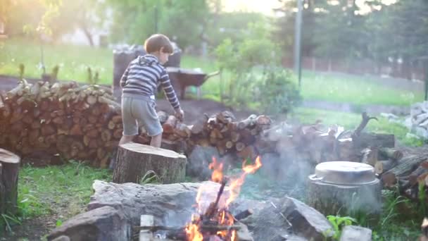 Ein Lagerfeuerkind wirft einen Baumstamm in die Luft — Stockvideo
