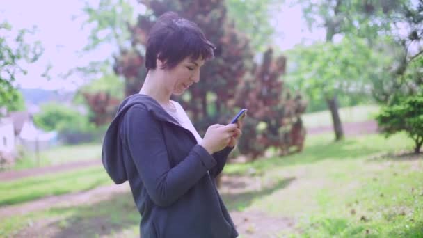 Porträtt flicka drömmar och skriver ett meddelande på smartphone — Stockvideo