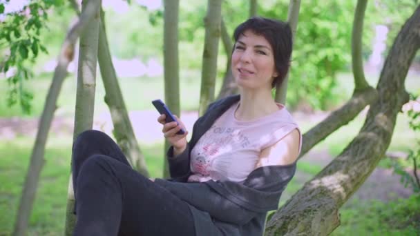 Девушка пользуется телефоном, разговаривая — стоковое видео