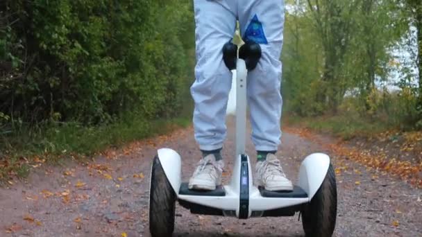 Junge im Astronautenkostüm steht auf einem Gyroscooter im nebligen Wald — Stockvideo