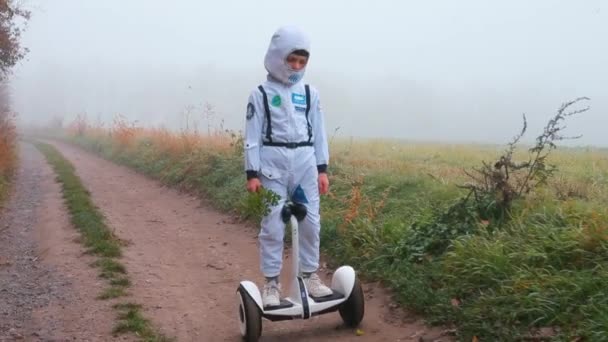 Un enfant, en costume d'astronaute, roule sur un gyroscooter . — Video