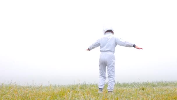 Un chico disfrazado de astronauta está tratando de volar en sus brazos hacia el cielo . — Vídeos de Stock