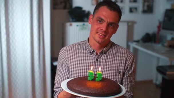 Der Kerl macht einen Geburtstagswunsch. mit einer Torte in der Hand. — Stockvideo