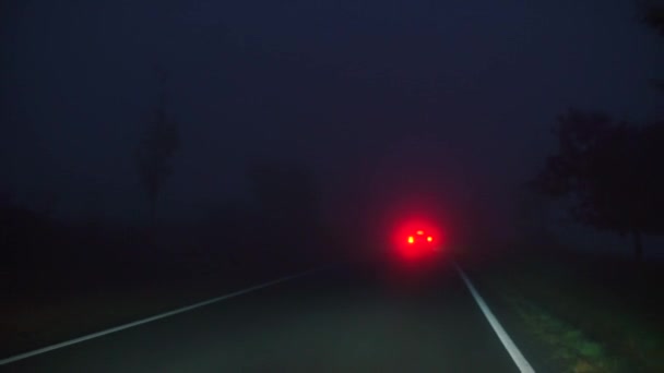 El coche se mueve en un camino de niebla por la noche — Vídeo de stock