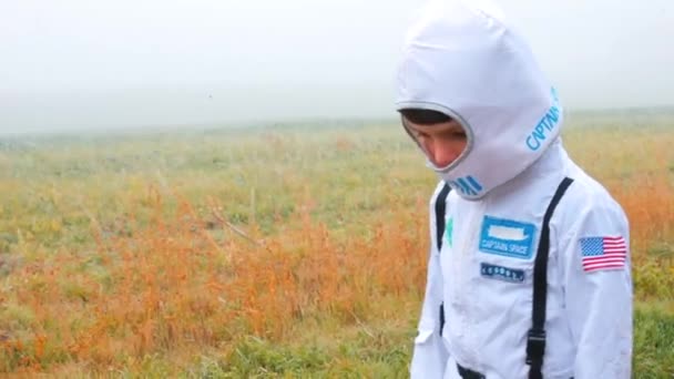 Un niño con un traje blanco y una máscara cabalga a través de un campo de niebla — Vídeos de Stock