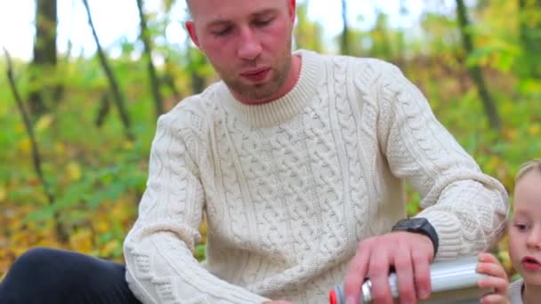 Táta nalévá svému synovi čaj na piknik v podzimním lese — Stock video
