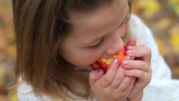 Close-up, uma menina rói uma maçã vermelha na floresta de outono — Vídeo de Stock