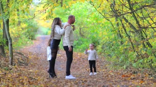 Przyjazna rodzina spaceruje po jesiennym lesie. — Wideo stockowe