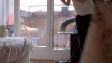 A child interacts playfully near a window, creating a warm atmosphere in a cozy home setting. Perfect for themes of childhood and family life.