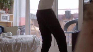 A relaxed scene of an individual moving indoors, showcasing a cozy living room atmosphere. Natural light enhances the inviting vibe.