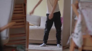 A young person in a casual outfit adjusts their clothing at home, showcasing comfort and daily routines in a relaxed indoor setting.