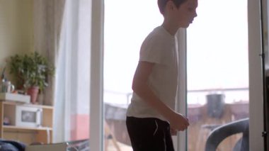 A young boy energetically jumping and playing indoors, showcasing joy and movement in a bright living space. Perfect for family and childhood themes.