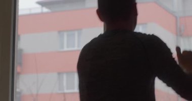 A person gazes out the window, lost in thought, while rain softly falls. Perfect for themes of reflection and solitude.