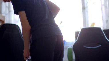 The video shows a man in a black shirt silhouetted by a window, contrasted with a woman vacuuming a chair, blending moments of stillness and action in a cozy home