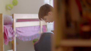 This video shows a young boy in his bedroom, engaging in various activities like tidying with a vacuum and reflecting in front of a bunk bed