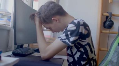 A highly stressed out teenager sits at a desk, struggling significantly with their challenging schoolwork on a computer