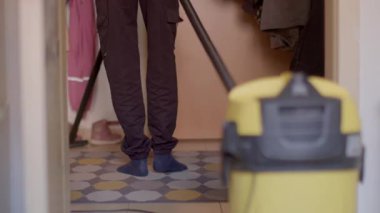 A person is diligently vacuuming their home while dressed in comfortable and casual attire, which helps create a tidy environment