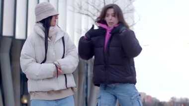 Two young women dance joyfully on a lively city street, embodying freedom. The scene shifts to a winter wonderland filled with festive dancing