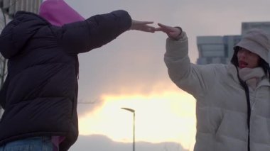 This touching video shows friends and couples making heart shapes with their hands at sunset, expressing love and connection amid a serene glow