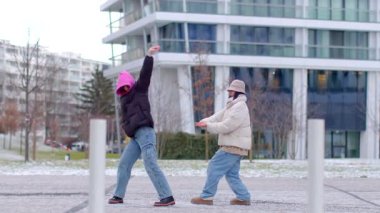 In an urban setting, joyful dance moments unfold in front of a building. A man and woman dance, joined by others, culminating in a romantic proposal