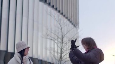 In this urban scene, individuals navigate the vibrant city. Two women chat outside a building, a stylish woman walks by, and a couple shares a moment