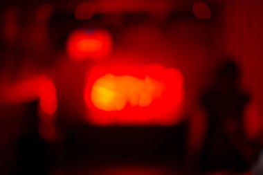 Yumuşak kırmızı ışıklar ve bulanık siluetler içeren büyüleyici bir soyut görüntü, sanatsal ve yaratıcı projeler için ideal..