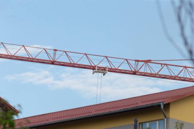 A striking construction crane stretches across a clear blue sky, capturing the essence of modern building projects in urban environments.