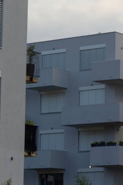 A sleek modern apartment building featuring balconies adorned with plants, showcasing contemporary architecture.