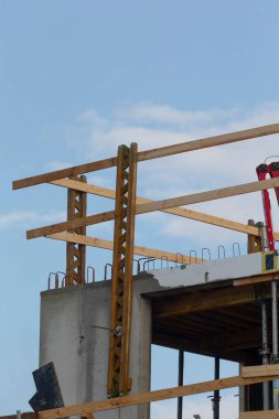 A detailed view of a construction site featuring wooden framework and concrete structure under a clear blue sky, showcasing modern building techniques.