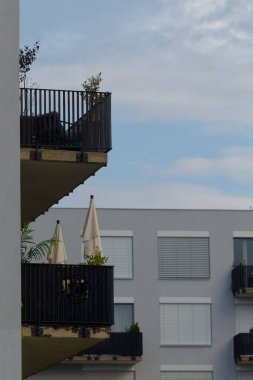 A view showcasing modern apartment balconies featuring sunshades and plants, captured against a blue sky. Ideal for urban architecture visuals.