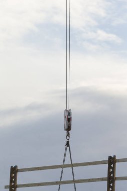 Centralized crane with pulley system used for lifting construction materials against a cloudy sky, showcasing industrial operations at height.