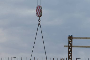 An industrial crane with a hook hanging down, ready for heavy lifting at a construction site, highlighting the tools of modern architecture and engineering.