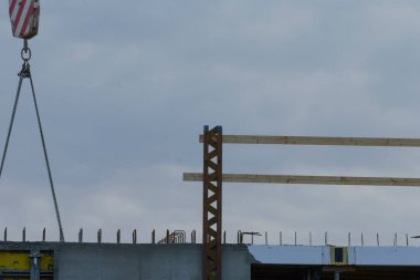 A construction site showcasing a crane lifting wooden beams against a cloudy sky.