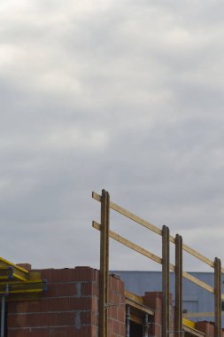 A construction site featuring brick walls with wooden beams, set against a backdrop of a cloudy sky, symbolizing progress and development.