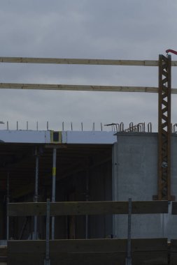 A view of an ongoing construction site featuring wooden beams and a concrete structure under a cloudy sky, showcasing modern building methods.