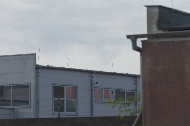 Bulutlu bir gökyüzüne karşı modern endüstriyel binalara bir bakış. Gösterişli çizgiler ve geniş pencereler, çağdaş kentsel tasarım sergileniyor.