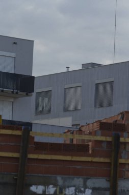 Çağdaş bir şehir binasında, inşaat malzemeleri ön planda istiflenerek kentsel gelişimi gösteren parlak tasarım unsurları yer almaktadır..