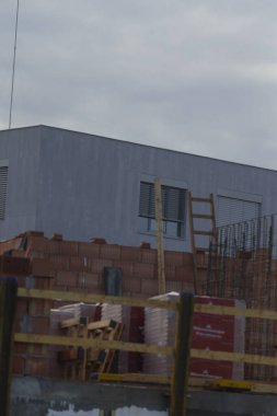 Tamamlanmamış bir bina, istiflenmiş malzemeler ve bir merdiven içeren bir inşaat alanı, kentsel inşaattaki gelişimi ve ilerlemeyi gözler önüne seriyor..