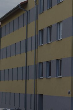 Çağdaş bir dış bina canlı sarı ve gri çizgiler sergiliyor, mimari tasarım ve kentsel estetiği vurguluyor.