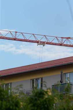 Çağdaş bir apartmanın üstünde kırmızı bir vinç kulesi var. Bölgede devam eden kentsel gelişim ve gayrimenkul gelişimi sergileniyor..