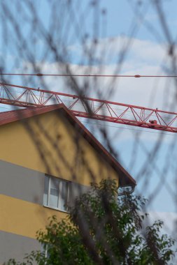 A snapshot of an urban construction site featuring a crane and a contrasting modern building against a clear sky.