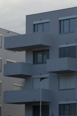 Balkon özellikleri ve geniş pencereli, minimalist mimari tasarım sergilenen modern bir konut binasının yakın çekim görüntüsü.
