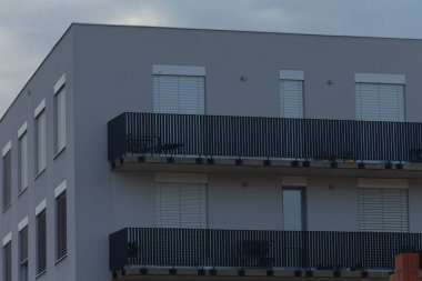 A contemporary architecture featuring a modern residential building with stylish balconies and sleek design against a cloudy sky.