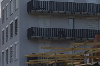 A contemporary apartment building featuring multiple balconies alongside a construction site. Ideal for urban development imagery.