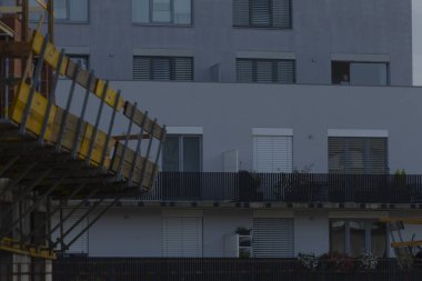An urban construction site captures a modern building facade with scaffolding and balconies, showcasing city architecture and development.