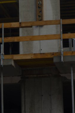 Ahşap iskeleli beton bir sütunu gösteren, modern yapı tekniklerini ve malzemelerini ön plana çıkaran bir inşaat sahasının yakın çekimi..